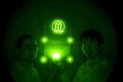 Zhengwei Pan and Feng Liu stand in a darkened room lit only by ceramic discs containing a persistent near-IR phosphor. The phosphorescent material was also mixed into the paint that was used to create the University of Georgia logo behind them. Imaging parameters: auto, ISO 200, and 3-4 seconds of exposure time using a night-vision monocular. Zhengwei Pan and Feng Liu stand in a darkened room lit only by ceramic discs containing a persistent near-IR phosphor. The phosphorescent material was also mixed into the paint that was used to create the University of Georgia logo behind them. Imaging parameters: auto, ISO 200, and 3-4 seconds of exposure time using a night-vision monocular.