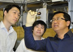 Iowa State physicist Jigang Wang, right, examines graphene monolayers grown on a substrate as graduate students Tianq Li, far left, and Liang Luo look on in Wang&apos;s laboratory.