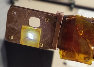 A yellowish platinum-rich polymer known as Pt-1 emits light as a laser beam hits it. The light appears white because the polymer emits a combination of broad-spectrum violet and yellow, which combine to appear white.