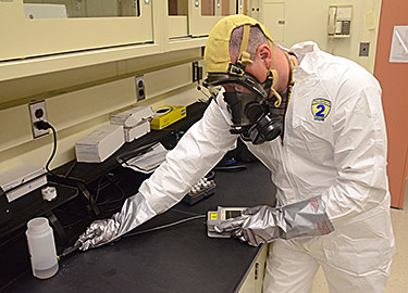 Christopher Neary of the NIST Environmental Management Group uses a handheld Raman spectrometer to determine the identity of an unknown sample.