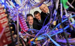 Irish Minister for Research and Innovation Sean Sherlock; Director of IPIC at Tyndall National Institute Prof. Paul Townsend; and Director General Science Foundation Ireland Prof. Mark Ferguson peer through a colorfully wired photonic system.