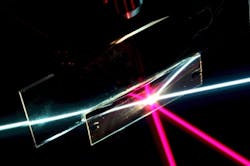 In this photo of the angular-selective sample (the rectangular region), a beam of white light passes through as if the sample was transparent glass. The red beam, coming in at a different angle, is reflected away, as if the sample was a mirror. The other lines are reflections of the beams. This setup is immersed in liquid filled with light-scattering particles to make the rays visible. In this photo of the angular-selective sample (the rectangular region), a beam of white light passes through as if the sample was transparent glass. The red beam, coming in at a different angle, is reflected away, as if the sample was a mirror. The other lines are reflections of the beams. This setup is immersed in liquid filled with light-scattering particles to make the rays visible.