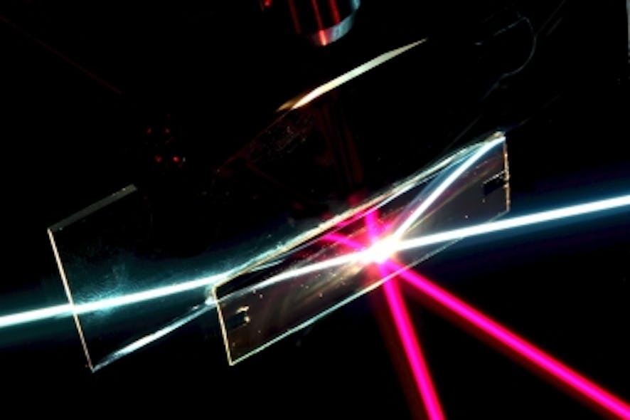 In this photo of the angular-selective sample (the rectangular region), a beam of white light passes through as if the sample was transparent glass. The red beam, coming in at a different angle, is reflected away, as if the sample was a mirror. The other lines are reflections of the beams. This setup is immersed in liquid filled with light-scattering particles to make the rays visible.