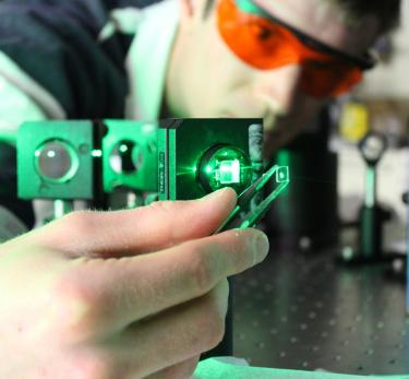 William Rice of LANL holds a crystal of strontium titanate up to the light. This crystal, previously thought to be nonmagnetic, can be magnetized using circularly polarized light at 400 to 500 nm wavelengths.