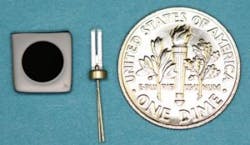 A new laser frequency reference (left) is a small 6 mm disk; a piezoelectric quartz tuning fork (center) is the frequency reference commonly used today in wristwatches to set the second. The dime (right) is for scale.