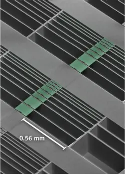 A scanning electron microscope image shows an array of optomechanical accelerometer devices with differing test-mass sizes. Highlighted green areas represent proof masses suspended by nanoscale tethers across the open, etched areas of the chip. The nanobeam cavities are seen as small square notches in the centers of the masses. A scanning electron microscope image shows an array of optomechanical accelerometer devices with differing test-mass sizes. Highlighted green areas represent proof masses suspended by nanoscale tethers across the open, etched areas of the chip. The nanobeam cavities are seen as small square notches in the centers of the masses.