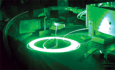 FIGURE 1. A raw coil of 100-&mu;m-core step index fiber delivering 40 W of green laser light illustrates the ability to input nearly unlimited amounts of RGB light into digital projectors and deliver up 500 W of visible light via optical fiber.