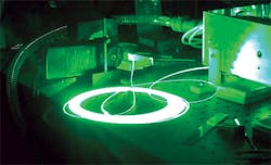 FIGURE 1. A raw coil of 100-μm-core step index fiber delivering 40 W of green laser light illustrates the ability to input nearly unlimited amounts of RGB light into digital projectors and deliver up 500 W of visible light via optical fiber. FIGURE 1. A raw coil of 100-μm-core step index fiber delivering 40 W of green laser light illustrates the ability to input nearly unlimited amounts of RGB light into digital projectors and deliver up 500 W of visible light via optical fiber.