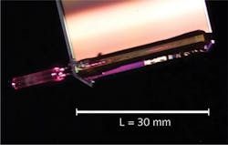 FIGURE 3. A SWIFTS chip is shown; on its left, a ferrule connects the entrance fiber to an optical die bonded to an imaging CMOS sensor. The chip is illuminated by a red laser to better see the waveguide. FIGURE 3. A SWIFTS chip is shown; on its left, a ferrule connects the entrance fiber to an optical die bonded to an imaging CMOS sensor. The chip is illuminated by a red laser to better see the waveguide.