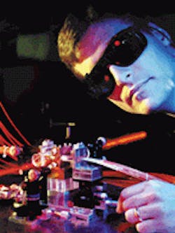 Pump light to this edge-pumped Nd:YAG zig-zag slab laser is delivered via the orange fibers from remotely located laser diodes. The tiny, barely visible laser crystal (1.5 x 4.5 mm cross section) is clamped between an upper and lower copper heat sink. In this configuration the gain medium is used as an amplifier, which is why the beam is shown on both sides. When operated as a laser, the setup produced an output of 127 W with a slope efficiency of 55%. Operator here is author Todd Rutherford. Pump light to this edge-pumped Nd:YAG zig-zag slab laser is delivered via the orange fibers from remotely located laser diodes. The tiny, barely visible laser crystal (1.5 x 4.5 mm cross section) is clamped between an upper and lower copper heat sink. In this configuration the gain medium is used as an amplifier, which is why the beam is shown on both sides. When operated as a laser, the setup produced an output of 127 W with a slope efficiency of 55%. Operator here is author Todd Rutherford.