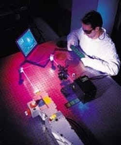 FIGURE 1. All-solid-state UV laser is used to machine the ball-grid array substrates that are being examined by this technician. The Inazuma Nd:YVO4 laser is specified to produce 8 W at 355 nm in a TEM00 beam with M2 < 1.3. FIGURE 1. All-solid-state UV laser is used to machine the ball-grid array substrates that are being examined by this technician. The Inazuma Nd:YVO4 laser is specified to produce 8 W at 355 nm in a TEM00 beam with M2 < 1.3.