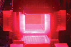 FIGURE 1. The 10-cm-square ceramic Nd:YAG slab at one end of Lawrence Livermore&rsquo;s solid-state heat-capacity laser glows from the pump light from the high-power pump arrays on four sides of the YAG slab, visible because the camera was not filtered to block the 808 nm pump wavelength. The camera did not record the 1064 nm output.