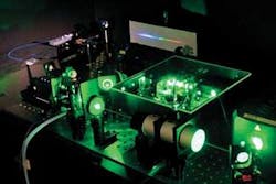 FIGURE 2. A modelocked Ti:sapphire laser (center) generates a frequency comb. The green light is scattered from the diode-pumped doubled-neodymium pump laser at right. The frequency comb is projected onto a screen in background; it looks like a rainbow-spanning continuum at this resolution.