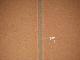 FIGURE 3. An ultrafast UV hybrid fiber laser can remove and pattern thin films of indium tin oxide (ITO) with processing speeds of 25 m/s (left). The sample shows straight walls with no signs of pulse overlapping as is often obvious with nanosecond lasers, and the bottom of the line is flat and there is no damage to the glass carrier (right).