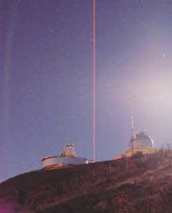 On a moonlit night, Nov. 21, 2002, the continuous-wave 589-nm sodium guidestar laser exits the auxiliary beam-director facility at the Starfire Optical Range (Kirtland AFB, NM). The beam is visible because of Rayleigh scattering of air molecules. The yellow beam is darkened because of a color shift of the digital camera.