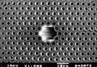 FIGURE 2. Single-mode photonic-bandgap fiber is constructed of hexagonally close-packed glass tubes having a 4.9-µm pitch and an air-fill fraction of 39%. Seven tubes are absent at the center of the fiber, forming a light-guiding air core 14.8 µm in diameter (top). When white light is launched into a 30-mm-long section of fiber, its core guides the portions of the broadband spectrum that lie within the fiber's photonic bandgap (bottom; green spot at fiber center). FIGURE 2. Single-mode photonic-bandgap fiber is constructed of hexagonally close-packed glass tubes having a 4.9-µm pitch and an air-fill fraction of 39%. Seven tubes are absent at the center of the fiber, forming a light-guiding air core 14.8 µm in diameter (top). When white light is launched into a 30-mm-long section of fiber, its core guides the portions of the broadband spectrum that lie within the fiber's photonic bandgap (bottom; green spot at fiber center).