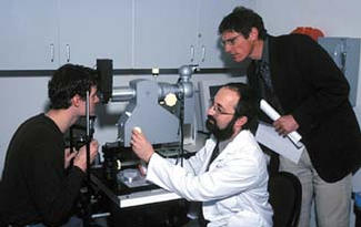 Researcher Werner Gellermann (right) and ophthalmologist Paul Bernstein (center) use resonance Raman spectroscopy to measure the macular pigment levels in the eyes of research assistant Steve Wintch (left) at the University of Utah's Moran Eye Center. The spectroscopy device is expected to help in the early detection and prevention of age-related macular degeneration.