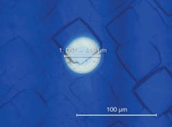 FIGURE 2. Picosecond lasers are now being used for selective removal of thin-film layers on crystalline silicon solar cells. This laser-ablation spot is shown against a solar-cell structure. FIGURE 2. Picosecond lasers are now being used for selective removal of thin-film layers on crystalline silicon solar cells. This laser-ablation spot is shown against a solar-cell structure.