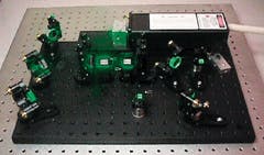 FIGURE 4. This 193-nm laser system prototype relies on an integrated pump laser that supplies about 25 millijoules of green input at 20 Hz to produce about 50 microjoules of output power. The CLBO crystal is in the foreground, mounted on a small rotation stage. The BBO crystal is positioned at the extreme right. The KTP OPO, in the center of the baseplate, shows two crystals inside the cavity. The pump laser is in the background. In this system the CLBO crystal is not yet mounted in a housing. It is removed from the system and placed in a dessicator when the system is not in operation.
