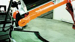 Robot-guided sealed carbon dioxide laser trims excess plastic laminate from the edges of an automobile windshield.