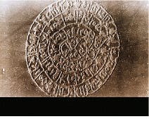 FIGURE 6. UV-emitting lasers have been used to etch microstructures pixel by pixel directly onto photoresists. This micrograph shows the Disk of Festos etched onto photoresist. The image is 200 × 200 pixels wide, with a pixel size of 3 µm. The total size is 0.6 mm—300 times smaller than the original—making this the smallest copy of the Disk of Festos ever made. The same technology—pixelated patterning by controlled microetching—is used to make microlens arrays. Festos was an ancient city in Crete, Greece. The disk dates from 1600 B.C. and is covered with hieroglyphics stamped into wet clay with a metal stamp—a very ancient precursor of printing. FIGURE 6. UV-emitting lasers have been used to etch microstructures pixel by pixel directly onto photoresists. This micrograph shows the Disk of Festos etched onto photoresist. The image is 200 × 200 pixels wide, with a pixel size of 3 µm. The total size is 0.6 mm—300 times smaller than the original—making this the smallest copy of the Disk of Festos ever made. The same technology—pixelated patterning by controlled microetching—is used to make microlens arrays. Festos was an ancient city in Crete, Greece. The disk dates from 1600 B.C. and is covered with hieroglyphics stamped into wet clay with a metal stamp—a very ancient precursor of printing.