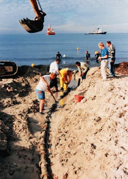 Undersea fiberoptic cable, part of the 27,300-km FLAG (Fiberoptic Link Around the Globe) network linking Europe, Africa, the Middle East, and Asia, is floated ashore from the cable-laying ship Nexus and buried on the beach at Palermo, Sicily. The network consists of eight sections of cable laid on the floor of the Mediterranean and Red seas and the Atlantic, Indian, and Pacific oceans. Cable will be buried 3 to 5 m deep in Hong Kong harbor because of the shipping traffic, and double-armored cable will be used in the South China Sea to protect the link from underwater turbulence. Undersea fiberoptic cable, part of the 27,300-km FLAG (Fiberoptic Link Around the Globe) network linking Europe, Africa, the Middle East, and Asia, is floated ashore from the cable-laying ship Nexus and buried on the beach at Palermo, Sicily. The network consists of eight sections of cable laid on the floor of the Mediterranean and Red seas and the Atlantic, Indian, and Pacific oceans. Cable will be buried 3 to 5 m deep in Hong Kong harbor because of the shipping traffic, and double-armored cable will be used in the South China Sea to protect the link from underwater turbulence.