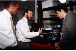 Shawn E. Burke (center), senior systems engineer at the Photonics Center at Boston University, describes a fiberoptic interface to Christopher P. Adams (left), chairman and CEO of Mosaic Technologies, and senior technician Mark Audeh.