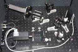 A lithium niobate waveguide (bottom left) combines a pump laser and a near-IR signal, up-converting the signal to a visible wavelength. Two prisms (right) separate the signal from the combined beam and send the signal to an avalanche-photodiode detector (top left), which reads the upconverted signal. A lithium niobate waveguide (bottom left) combines a pump laser and a near-IR signal, up-converting the signal to a visible wavelength. Two prisms (right) separate the signal from the combined beam and send the signal to an avalanche-photodiode detector (top left), which reads the upconverted signal.