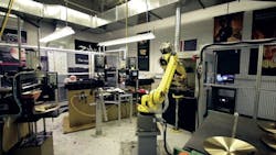 FIGURE 2. A Fanuc robot loads a cymbal into a laser marking workstation. FIGURE 2. A Fanuc robot loads a cymbal into a laser marking workstation.