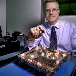 An integrated photonic circuit with a size similar to the chip held by NASA researcher Mike Krainak will replace the fiber-optic receiver in the lower portion of the photo. The new modem will be tested on the International Space Station.