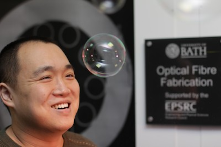 Fei Yu from the University of Bath helped develop the new hollow-core optical fiber that lases in the mid-infrared region. The long and thin bubbles of glass in the fiber reflect light into the fiber’s core in a similar way to how light reflects off the surface of a soap bubble, making it appear iridescent. (Image credit: University of Bath)