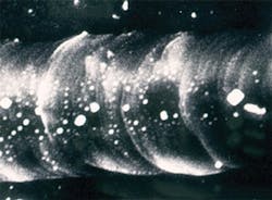 FIGURE 2. A secondary electron micrograph shows grains of KBr remaining embedded in the melted diamond after the face was rinsed in water. FIGURE 2. A secondary electron micrograph shows grains of KBr remaining embedded in the melted diamond after the face was rinsed in water.