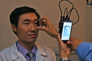 Dr. Bailey Shen, a resident in the department of ophthalmology and visual sciences in the UIC College of Medicine, has his retina photographed using a camera based on the Raspberry Pi 2 computer.