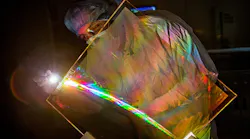 Marcus Monticelli inspects the anti-reflective coating on a National Ignition Facility grating debris shield. The coating restores lost NIF energy and eliminates a source of optics damage.