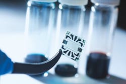 A new flexible graphene solar cell developed at MIT is seen in the transparent region at the center of this sample. Around its edges are metal contacts on which probes can be attached during tests of device performance. A new flexible graphene solar cell developed at MIT is seen in the transparent region at the center of this sample. Around its edges are metal contacts on which probes can be attached during tests of device performance.