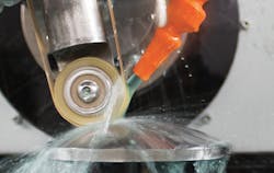 FIGURE 3. Here, a silicon asphere is being polished with a CeO belt and coolant to aid material removal. FIGURE 3. Here, a silicon asphere is being polished with a CeO belt and coolant to aid material removal.