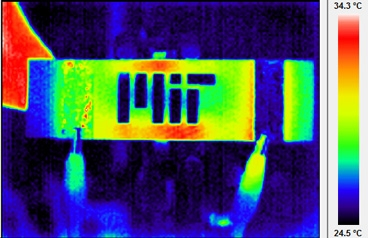 Infrared themographic image of a nanoengineered composite heated via electrical probes (clips can be seen at bottom of image). The MIT logo has been machined into the composite, and the hot and cool spots around the logo are caused by thermal-electrical interactions of the resistive heating and the logo 'damage' to the composite.