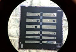 A magnified photograph shows a semiconductor chip containing arrays of crystalline coated micro-cantilevers used to create an experimental apparatus for measuring quantum radiation pressure noise. A magnified photograph shows a semiconductor chip containing arrays of crystalline coated micro-cantilevers used to create an experimental apparatus for measuring quantum radiation pressure noise.