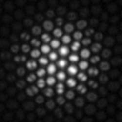 FIGURE 2. A defocused fluorescent point source is imaged through an optical fiber bundle. Different modal patterns encode spatially varying angular ray distributions. The central cores carry mostly normally incident light that couples to the fundamental modes of the cores. Higher-angle-of-incidence light that arrives at the periphery of the defocused spot is transmitted mainly by higher-order modes, visible as lobed structures or rings. FIGURE 2. A defocused fluorescent point source is imaged through an optical fiber bundle. Different modal patterns encode spatially varying angular ray distributions. The central cores carry mostly normally incident light that couples to the fundamental modes of the cores. Higher-angle-of-incidence light that arrives at the periphery of the defocused spot is transmitted mainly by higher-order modes, visible as lobed structures or rings.