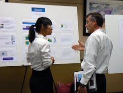 FIGURE 1. Graduate student Baijie Gu (left) discusses recent research with a company representative at the semi-annual Industrial Affiliates Workshop at the University of Arizona College of Optical Sciences.