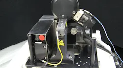 A miniature MRF polishing head with an improved fluid-delivery system is small enough to fit on an end table. The polishing wheel is at the top; the ribbon of MR fluid is held on the wheel’s rim.