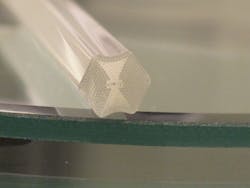 A PHOSFOS photonic-crystal fiber (shown here as a preform) will be patterned with Bragg gratings and be embedded in a flexible polymer skin for sensing (top). An experimental polymer skin, illuminated with a supercontinuum source, is wrapped around a surface to be monitored (bottom). A PHOSFOS photonic-crystal fiber (shown here as a preform) will be patterned with Bragg gratings and be embedded in a flexible polymer skin for sensing (top). An experimental polymer skin, illuminated with a supercontinuum source, is wrapped around a surface to be monitored (bottom).