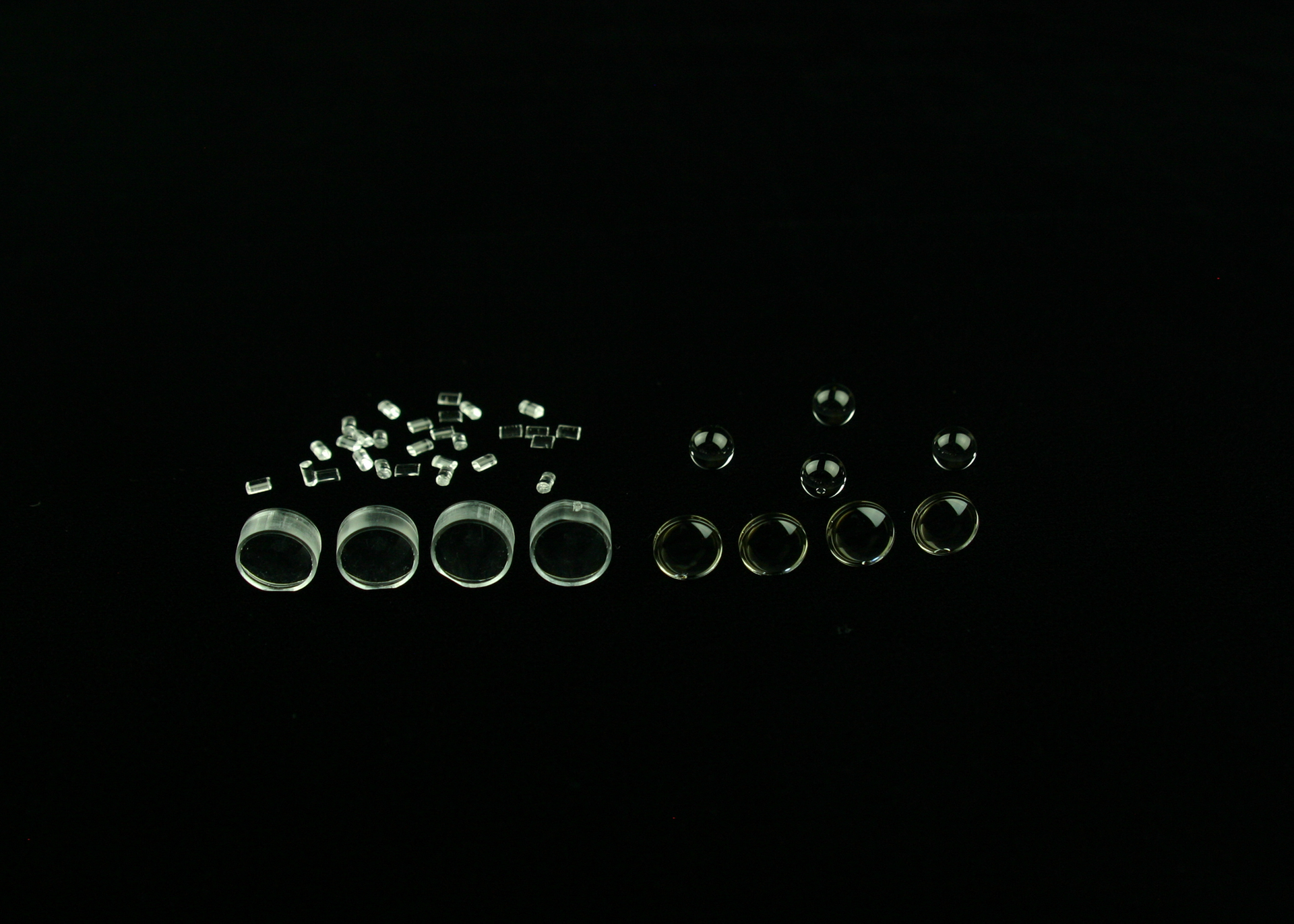 FIGURE 1. Molded optics can start with raw materials made of plastic (left) or glass (right). Thermoplastic resins for plastic optical injection molding are provided in extruded and cut pellet form. The PGM process requires a precision preform prior to molding.