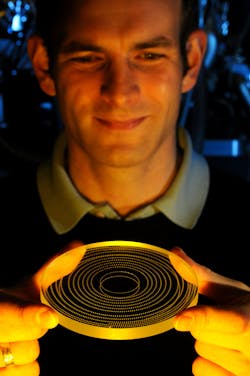 Patrick Heissler, lead author of the study, holds a silica blank; plasma formation destroys small regions on the rotating blank.