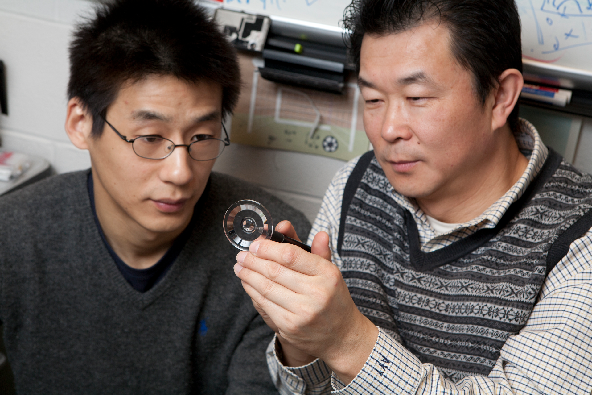 FIGURE 1. Allen Yi and Lei Li inspect a prototype lens that can be used to create three-dimensional images.