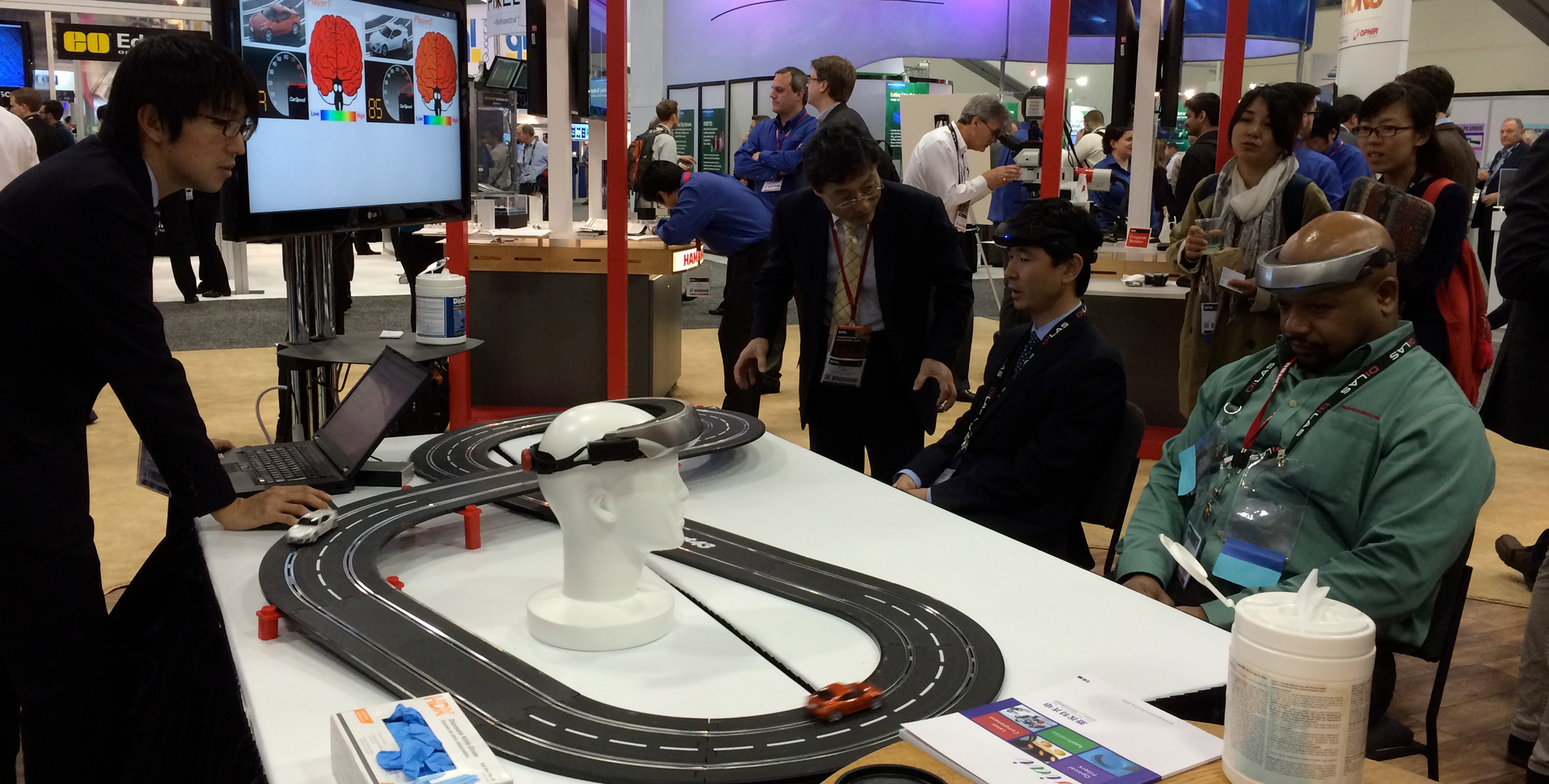 FIGURE 1. At SPIE Photonics West 2015, Hamamatsu's booth featured a double-track toy car racing game setup that involved two 'racer' participants, who would each wear an electronic headband incorporating a NIRS optical probe able to wirelessly send signals to one of the cars on the track.