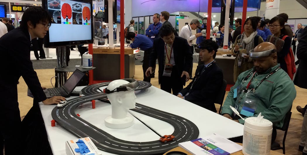 FIGURE 1. At SPIE Photonics West 2015, Hamamatsu&apos;s booth featured a double-track toy car racing game setup that involved two &apos;racer&apos; participants, who would each wear an electronic headband incorporating a NIRS optical probe able to wirelessly send signals to one of the cars on the track.