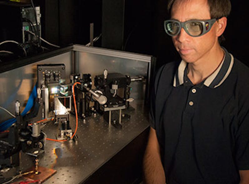NIST engineer Tasshi Dennis sits next to NIST&apos;s solar simulator based on a white-light supercontinuum laser. The instrument simulates sunlight to help measure the properties of solar cell materials. The instrument&apos;s beam is illuminating a gallium arsenide solar cell in the lower left corner of the photo.
