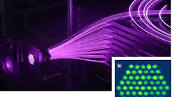 FIGURE 1. Shown are XCAN’s 61 Yb-doped fiber amplifier bundle (a) and its near-field interference pattern (b).