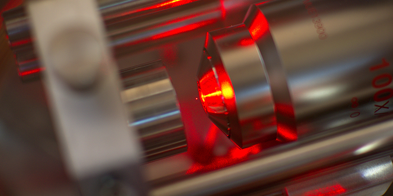 A microscope objective focuses laser light to create optical tweezers in which a nanosphere (minuscule red dot iat the center of the image) is levitated.